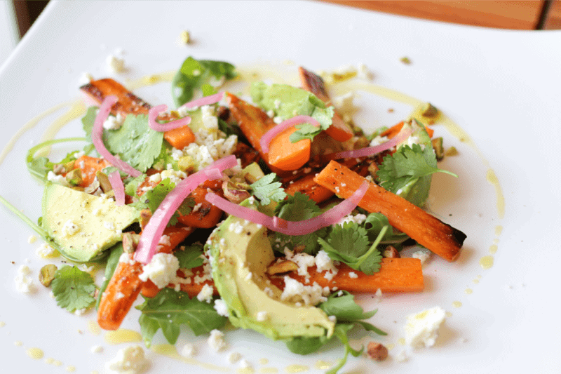 salade carotte grillée et avocat avec roquette dans une assiette blanche
