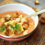 gaspacho dans un joli bol blanc avec croutons, oeuf cuit dur en dés et herbes vertes