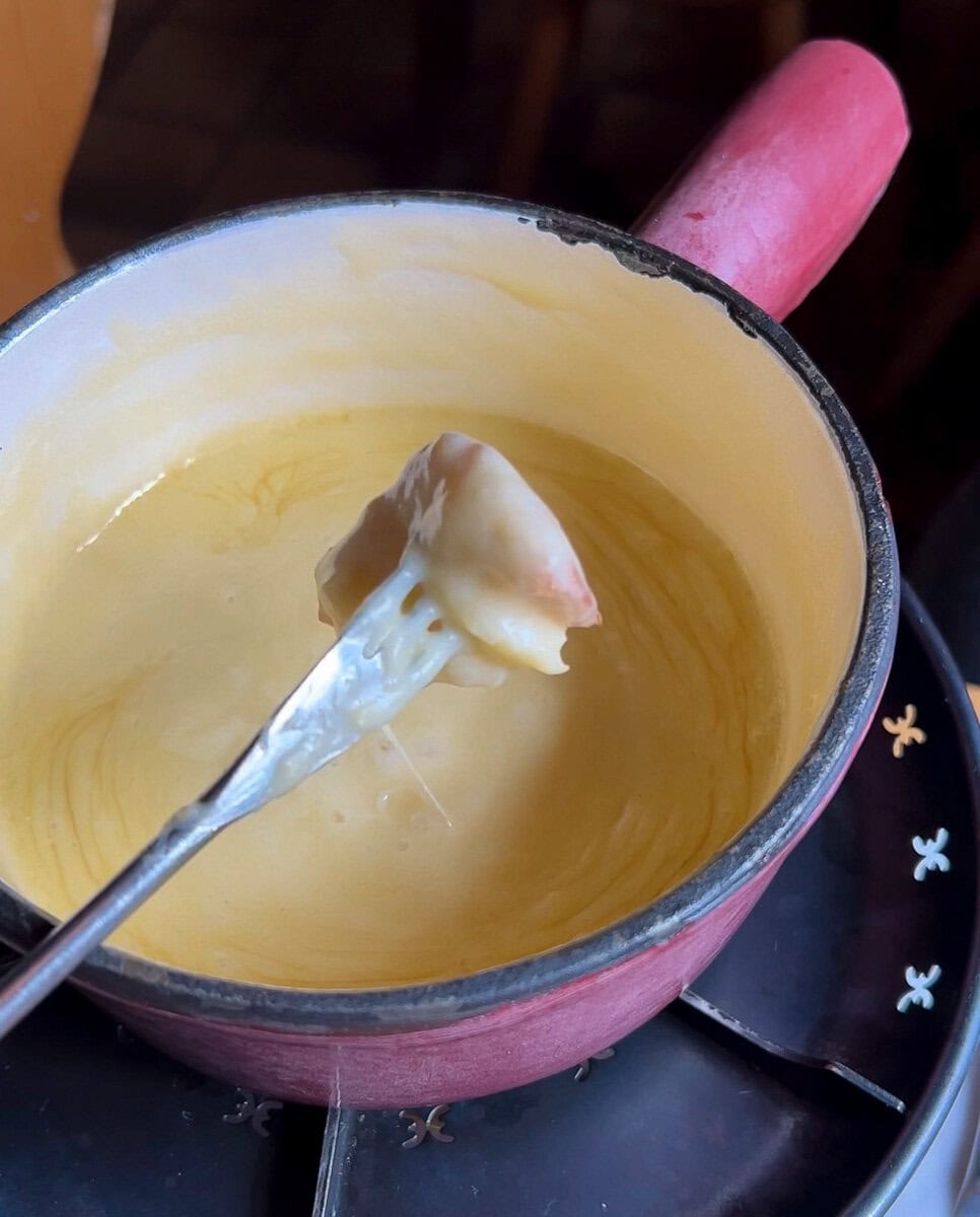 fondue au fromager dans un caquelon, dés de pain sur fourchette à fondue