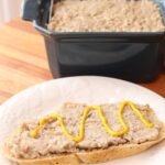recette de cretons traditionnels avec moutarde sur une tranche de pain avec terrine en arrière plan