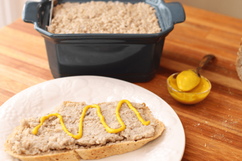 cretons sur une tranche de pain avec moutarde, terrine en arrière plan