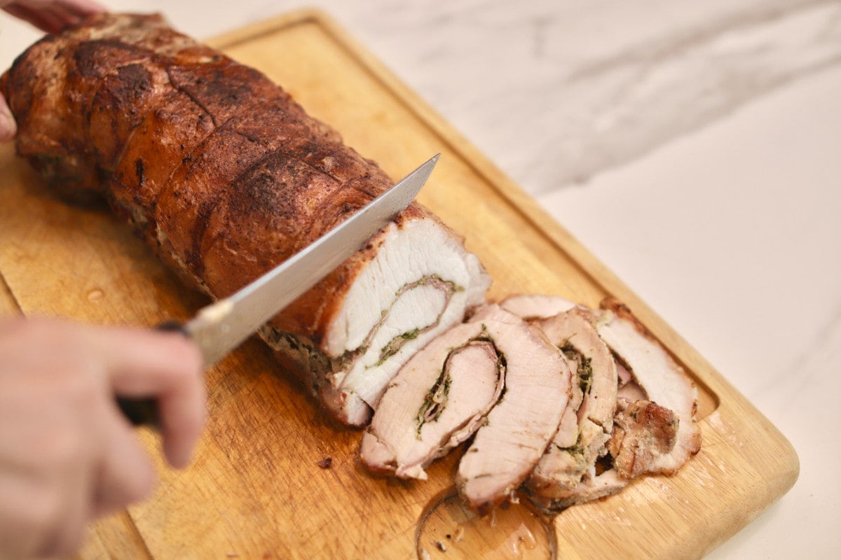 porchetta de longe de porc sur une planche à découper, en fines tranches