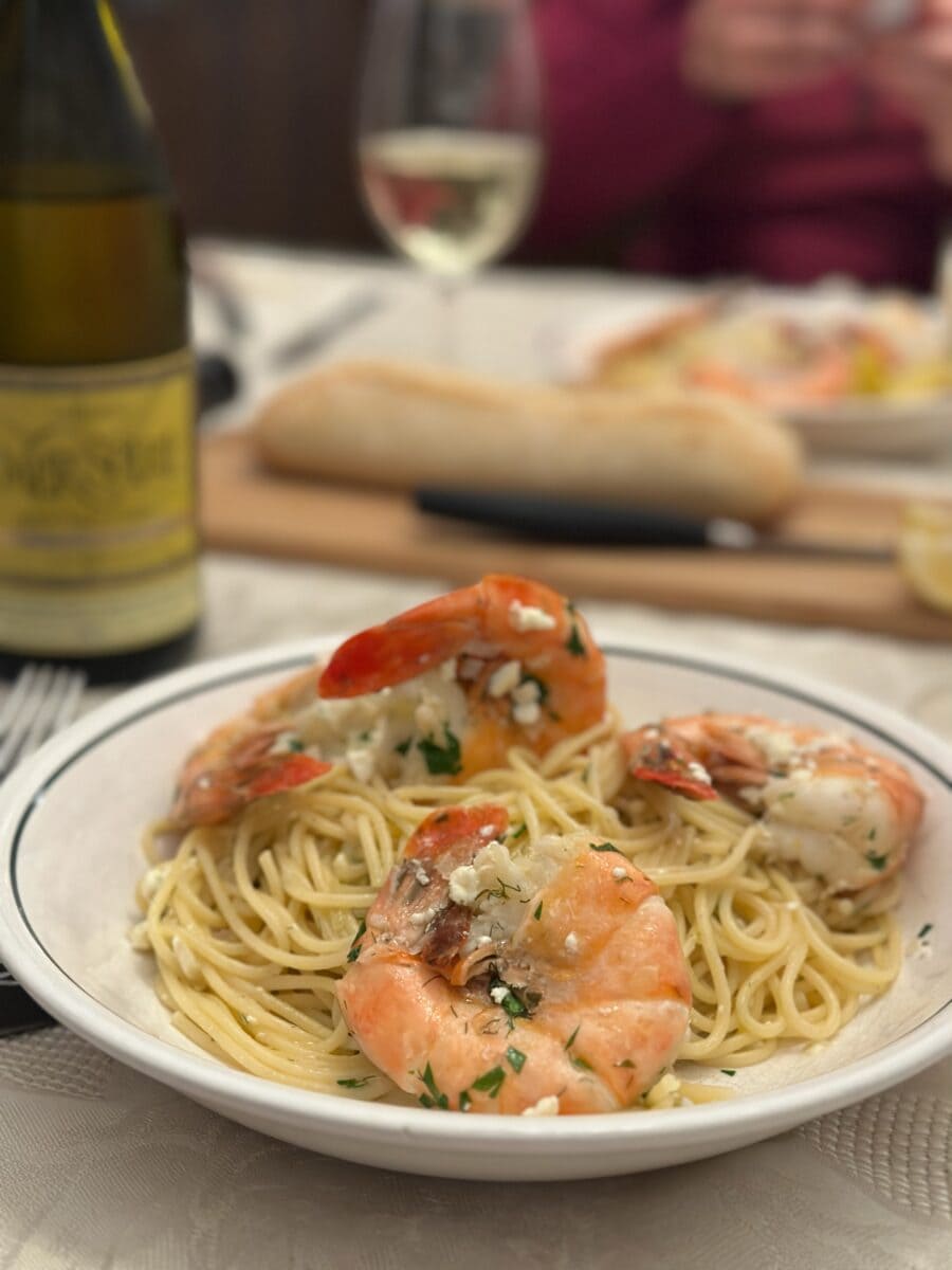 bol de spaghetti aux crevettes sur une table avec bouteille de vin en arriere plan