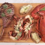 tomahawk et homard sur une planche avec beurre composé