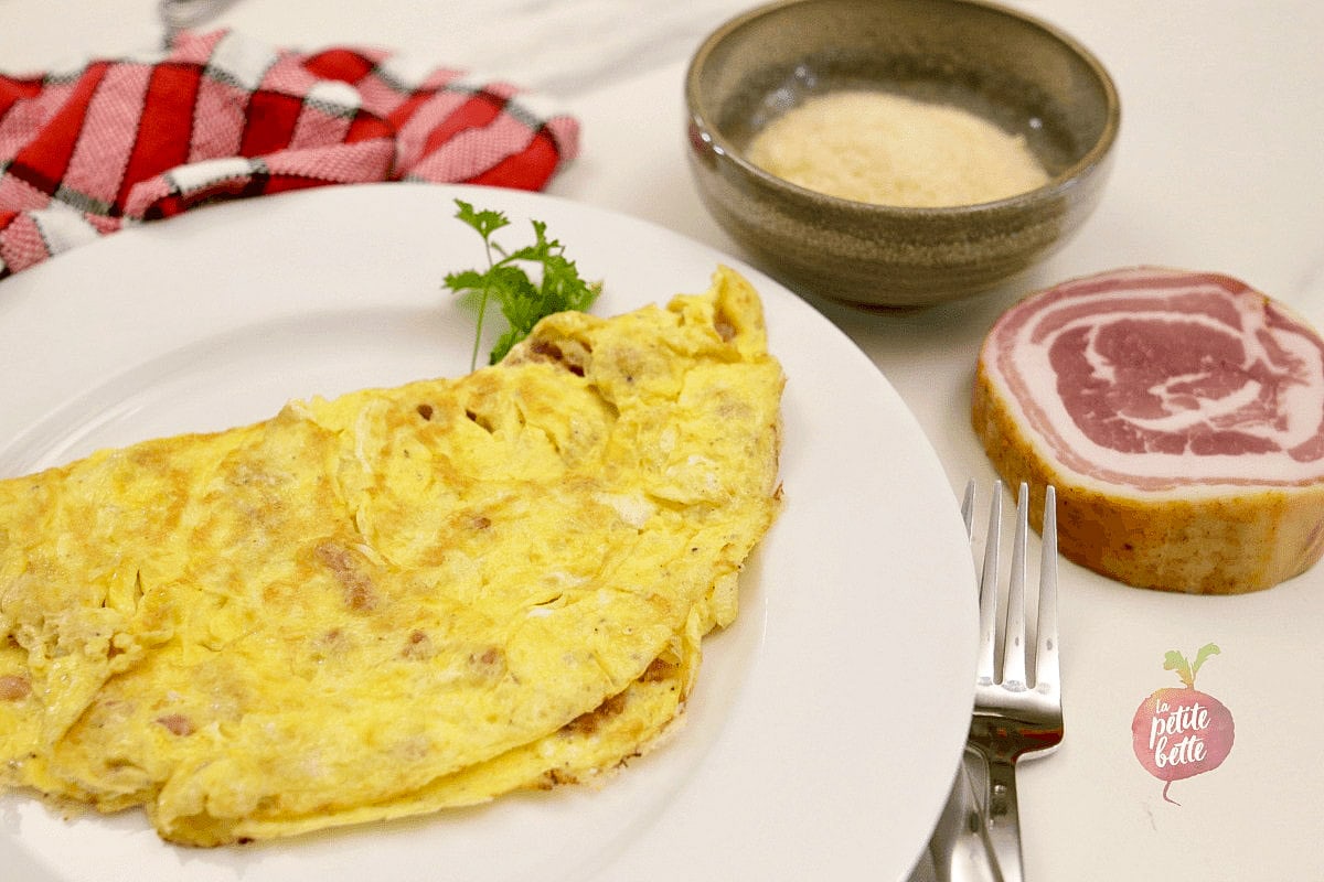 omelette avec fromage et pancetta dans une assiette avec persil et linge de table en arrière plan