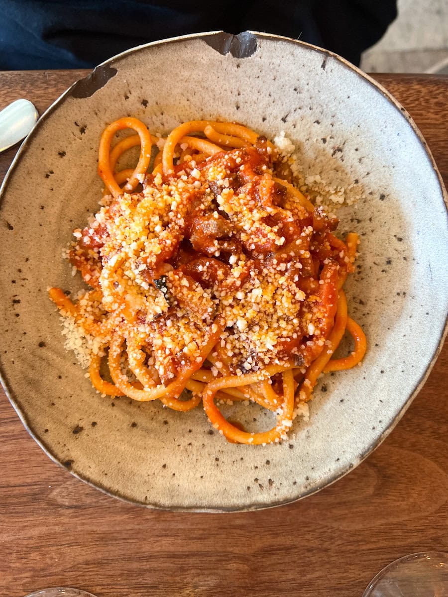 bol de buccatini sauce bolognaise avec du parmesan rapé