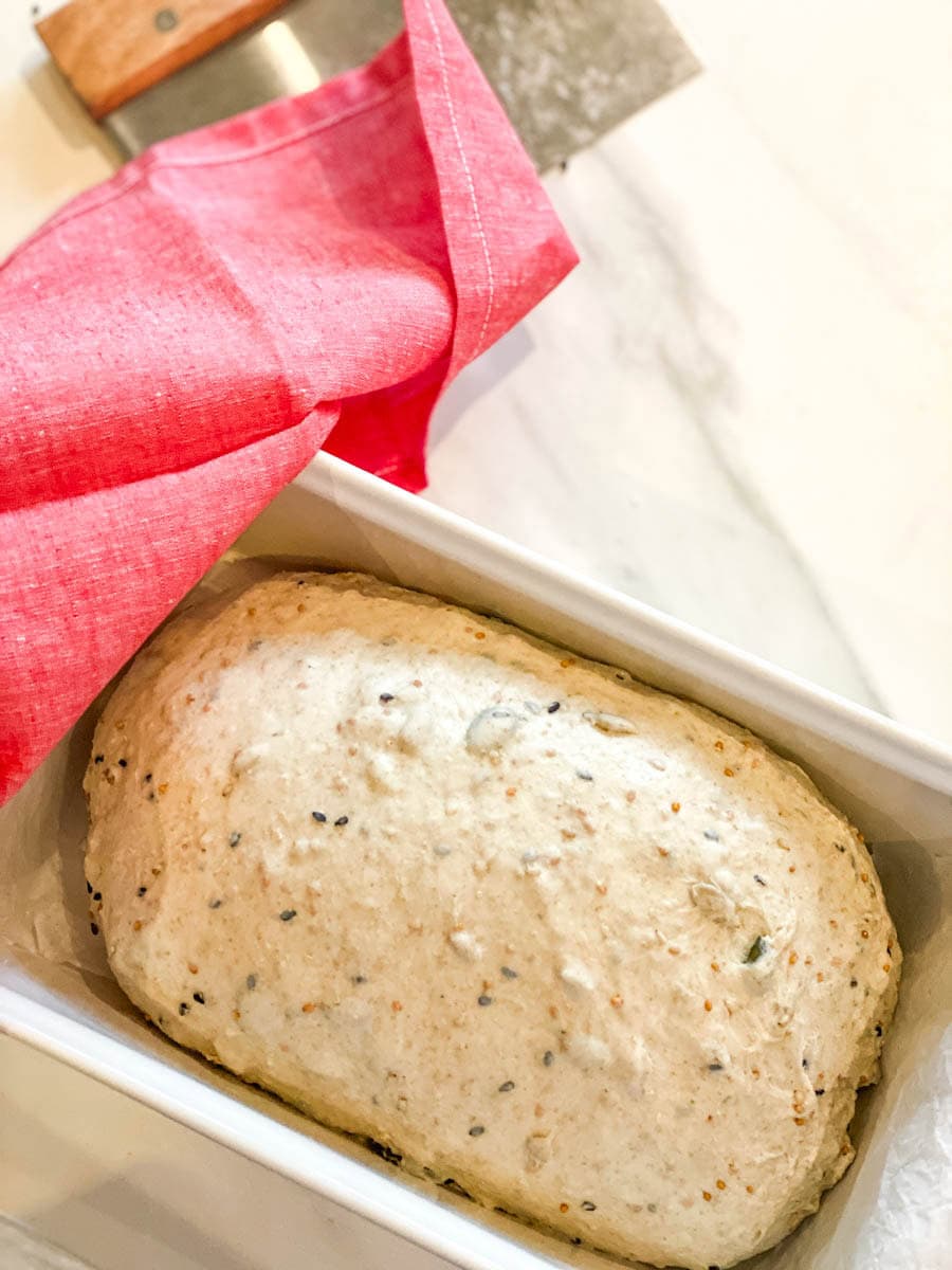 Pain multigrain en moule à pain avec linge rouge et couteau à pâte