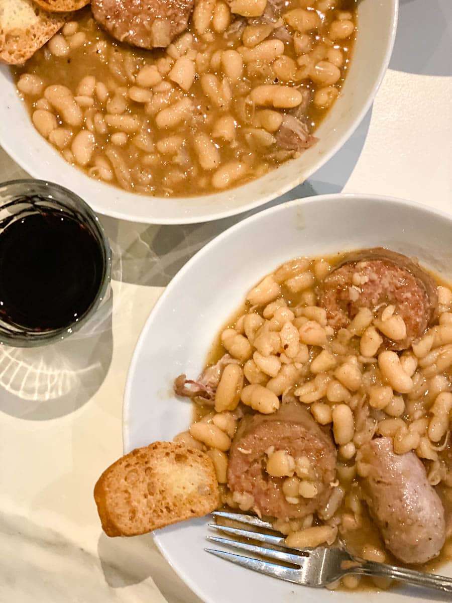 cassoulet dans deux bols avec verre de vin et petit croûton de pain grillé