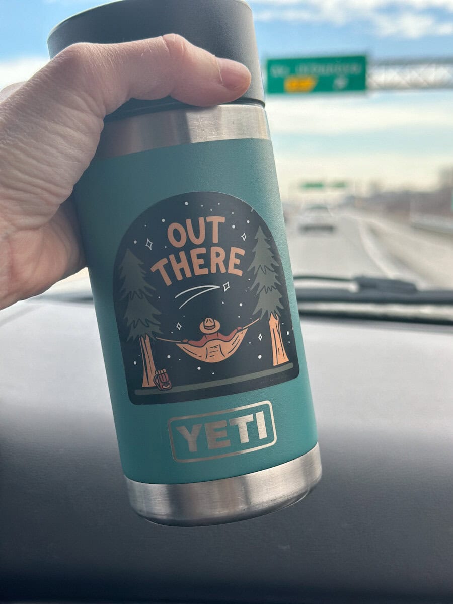 Main qui tient une tasse a café Yeti en voiture
