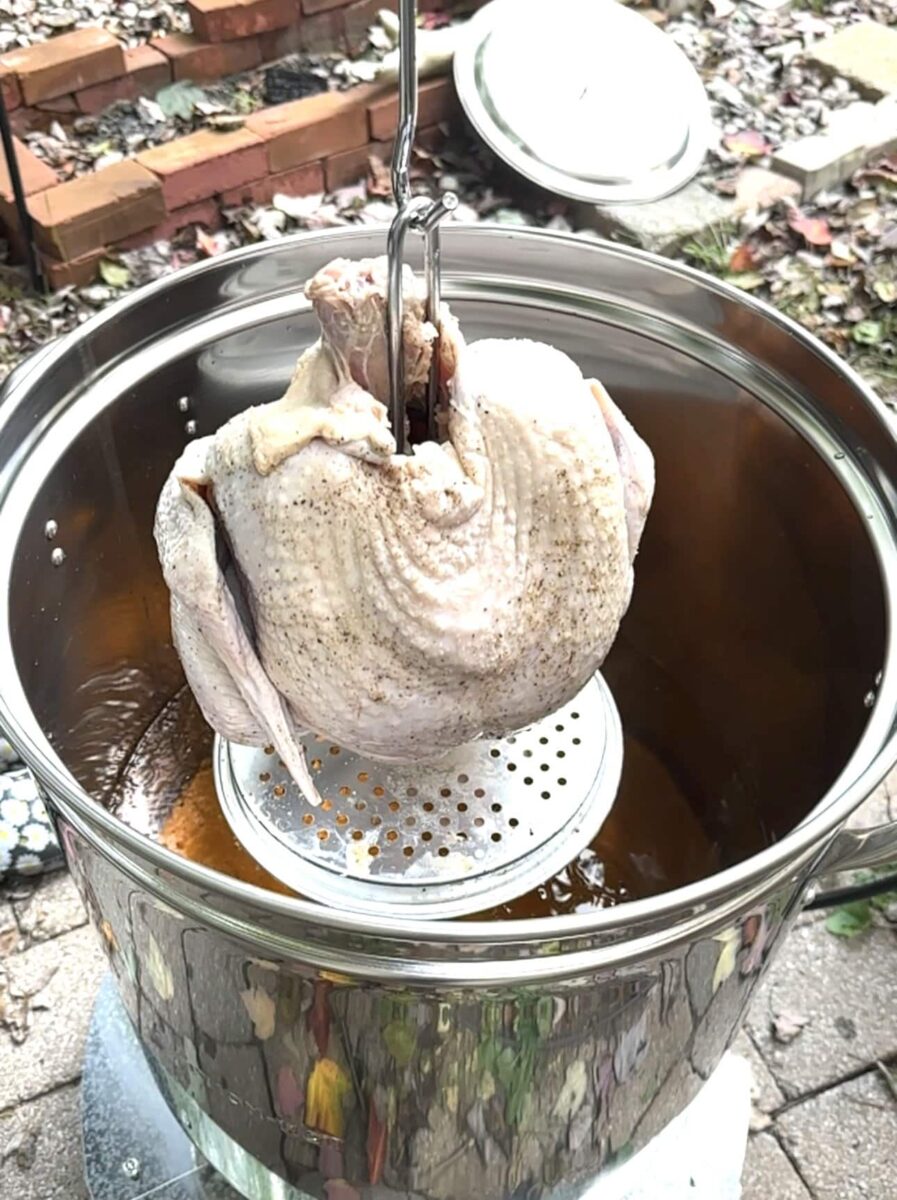 dinde entière non cuite qui plonge dans casserole d'huile