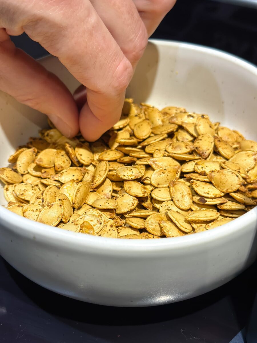 graines de citrouille grillées et assaisonnées dans un bol avec une main