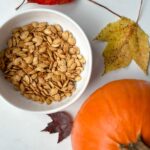 graines de citrouille grillées dans un bol avec petite citrouille et feuilles d'automne