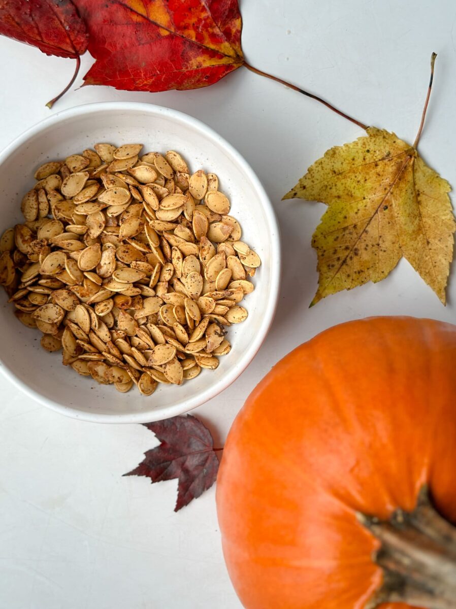 graines de citrouille grillées dans un bol avec petite citrouille et feuilles d'automne