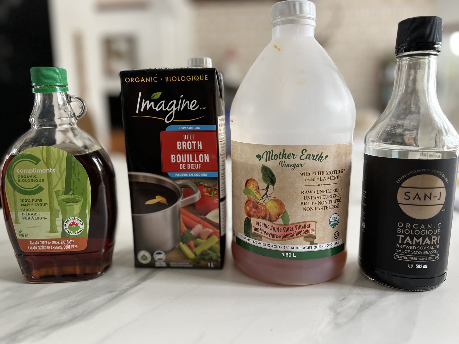 ingrédients sur le comptoir: vinaigre de cide, bouillon, sauce tamari et sirop d'érable 