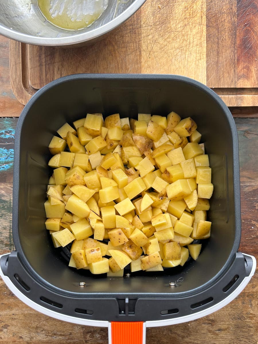 pommes de terre à dejeuner non cuites, en dés, dans le panier du air fryer sur une table