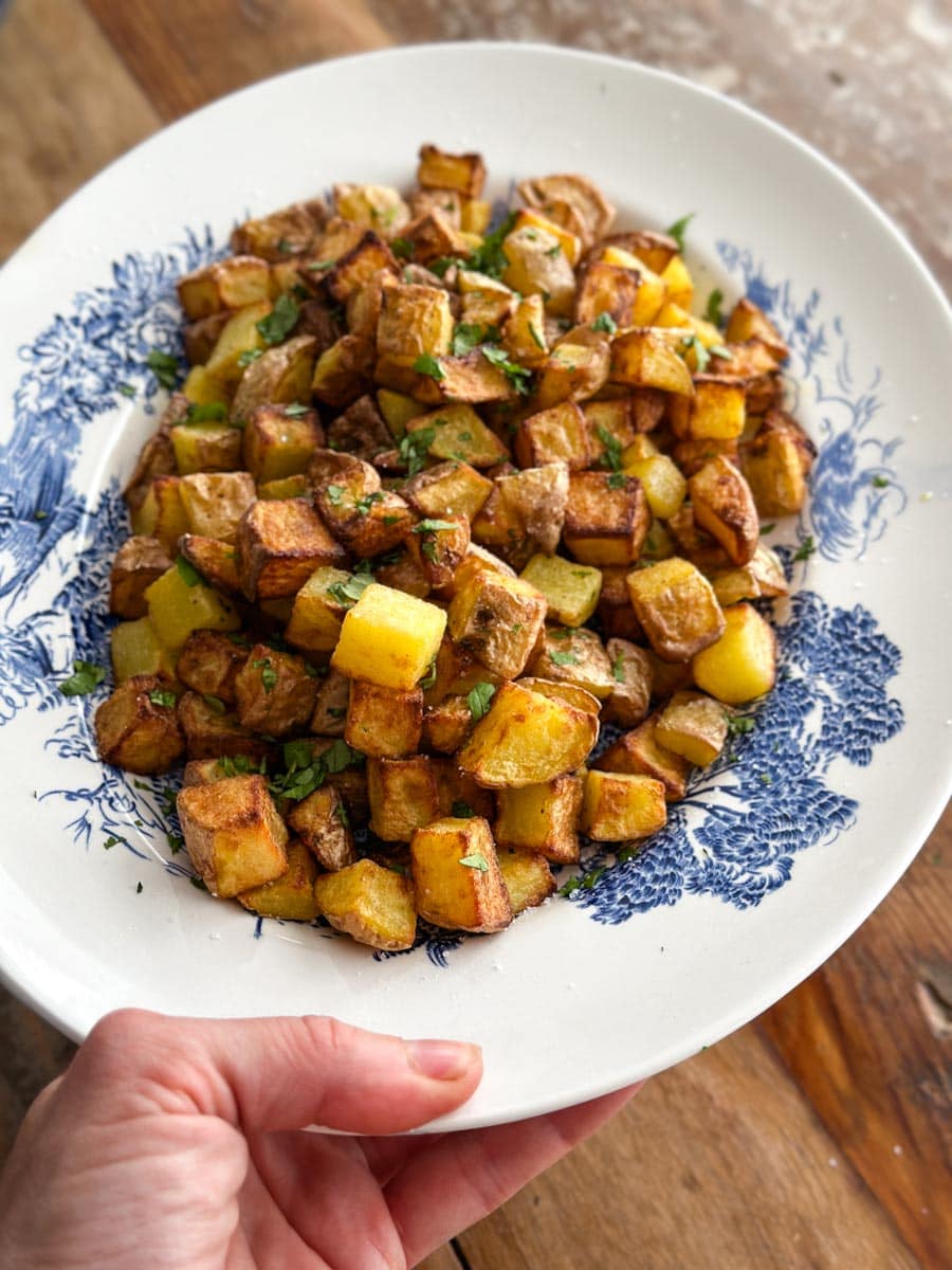 main tenant l'assiette de patates déjeuner grillées