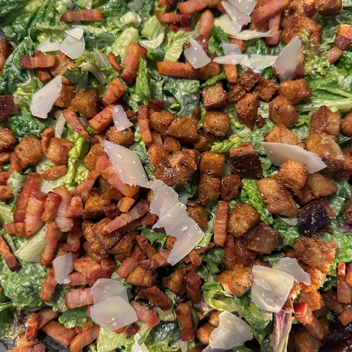 salade cesar, bacon, croûtons, fromage parmesan, laitue vue de près 