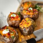 pommes de terre farcies toutes garnies, avec fromage, bacon, oignons verts, cuite au air fryer, sur une planche