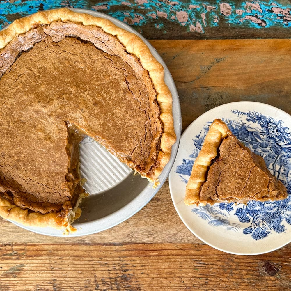 tarte au sucre coupée, une pointe dans une assiette, sur table en bois