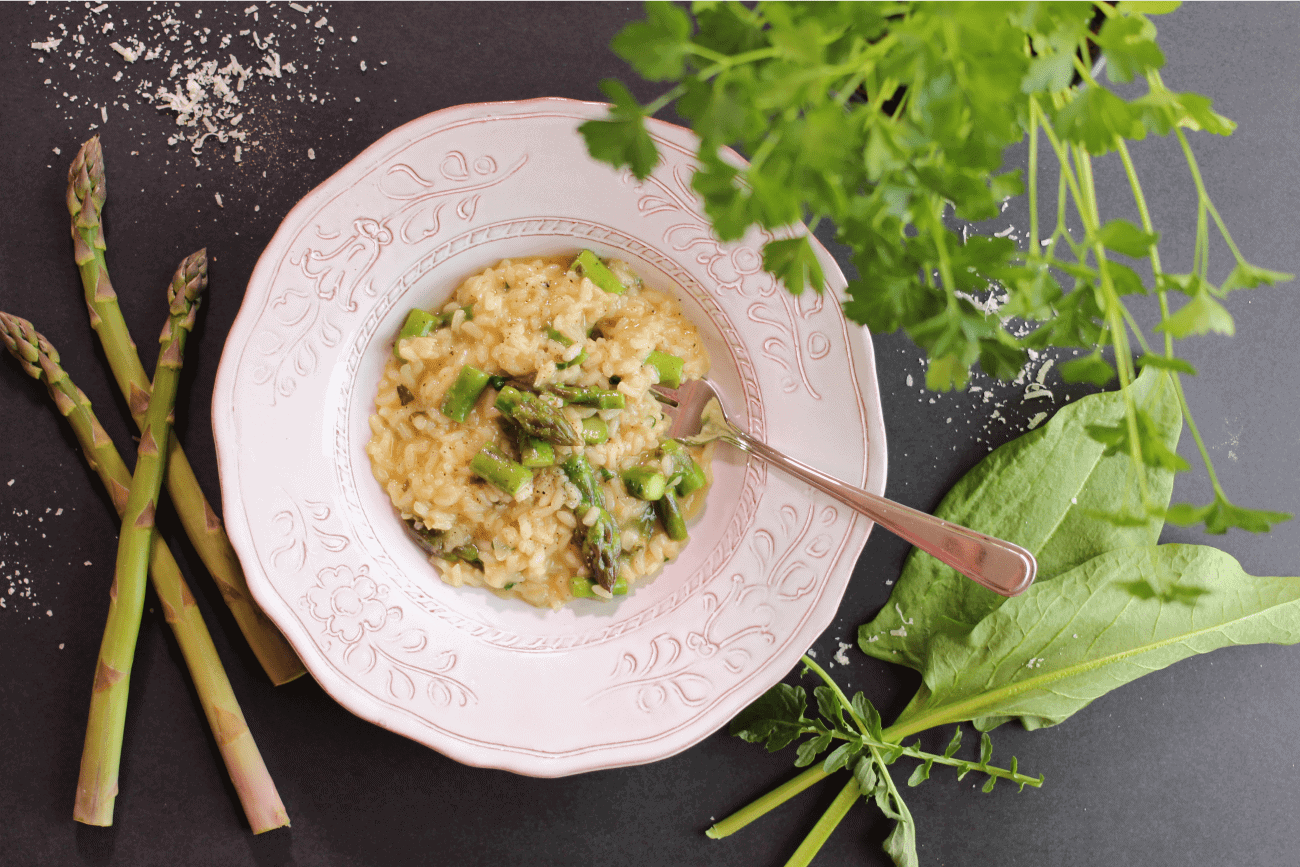 risotto aux asperges et citron dans un bol avec asperge, herbes sur une table