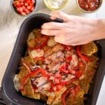 main qui prend des nachos au poulet dans le panier du air fryer