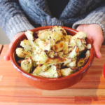choufleur roti dans un plat en tere cuite tenu par deux main
