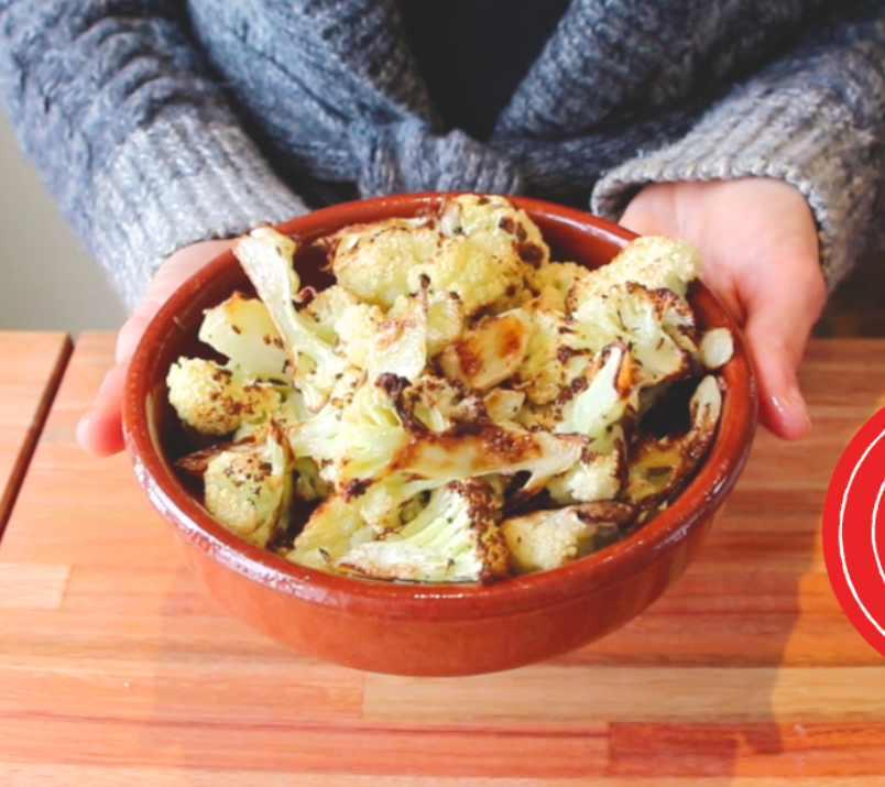 choufleur roti dans un plat en tere cuite tenu par deux main