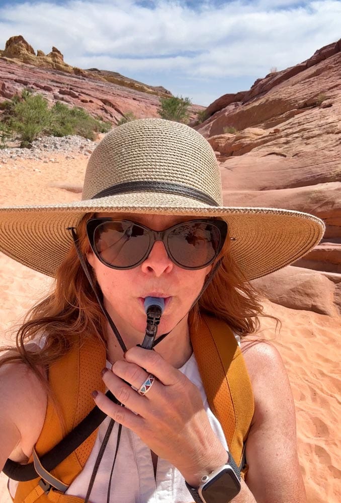 Manon Lapierre lunette soleil, chapeau, sac à dos et tube d'hydratation dans la bouche