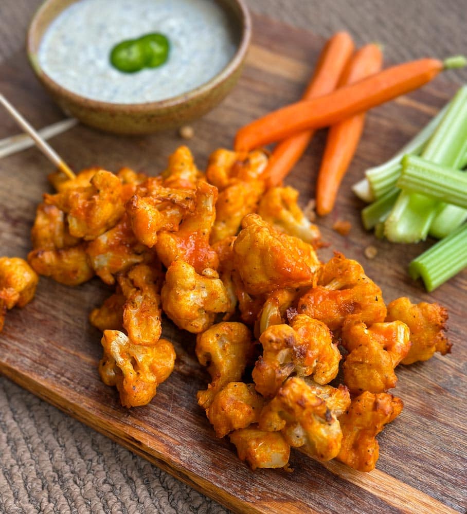 bouchées de chou fleur buffalo à l'air fryer sur une planche avec crudités et trempette ranch