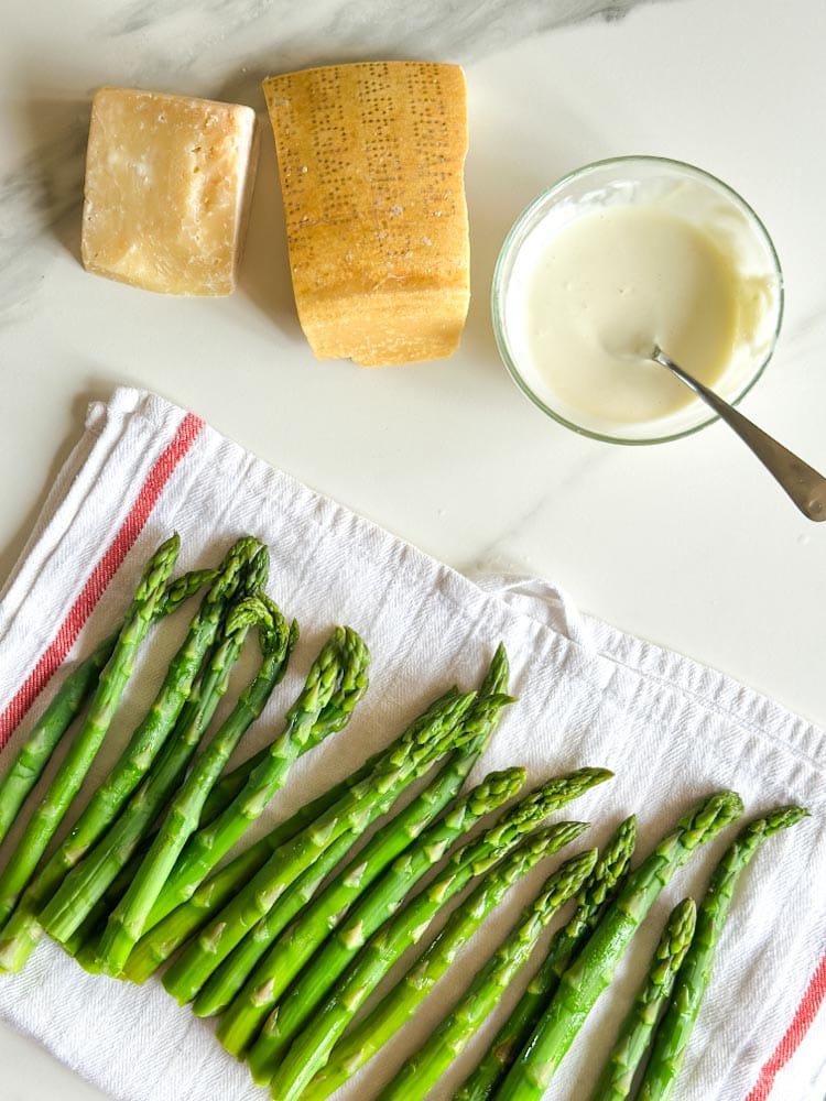 asperges prêtes pour la vinaigrette sur un linge propre avec vinaigrette et parmesan