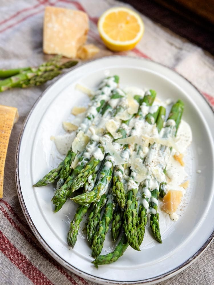 asperges dans une assiette ovale avec vinaigrette et fromage parmesan