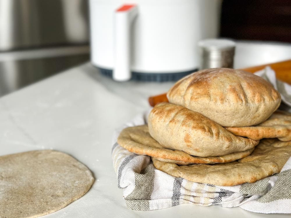 pain pita cuit sur le comptoir, une pâte non cuite et air fryer en arrière plan