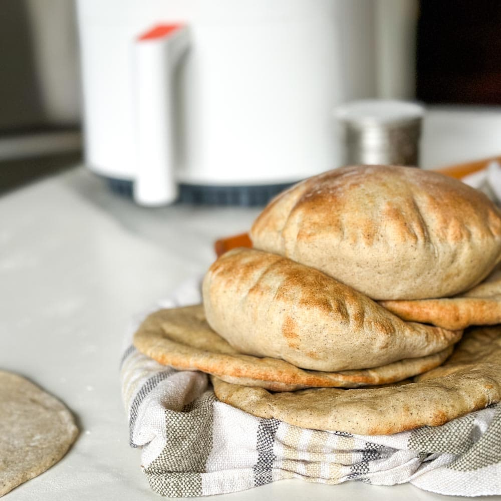 pains pita sur un linge devant un air fryer blanc