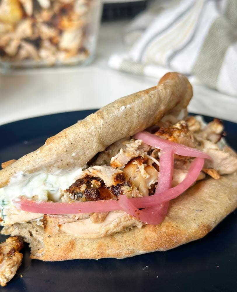 sandwich shish taouk sur pain pita avec sauce tzaziki et oignon rouge dans une assiette noire