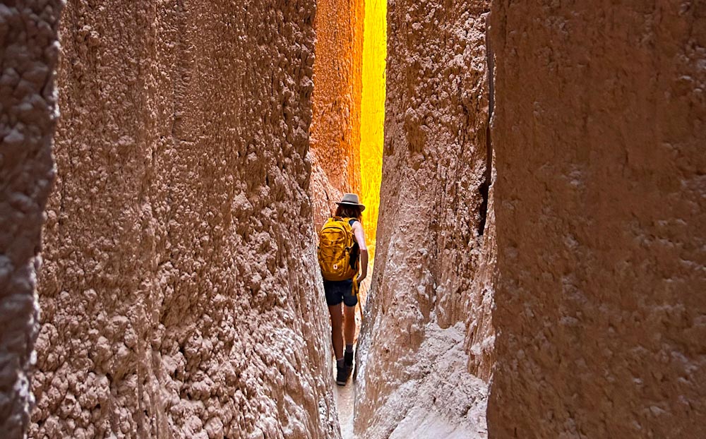 Manon Lapierre dans une grotte de dos, sac à dos, lumière orange derrière