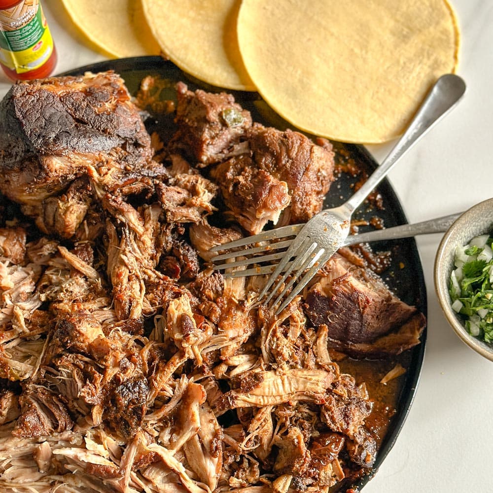 porc effiloché mexicain cuit à la mijoteuse style tacos birria, avec fourchettes et tortillas