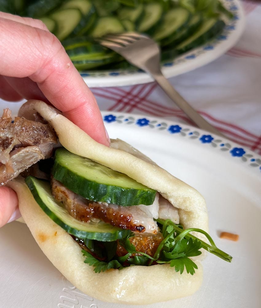 pain bao fait maison avec porc croustillant et concombre dans une main 