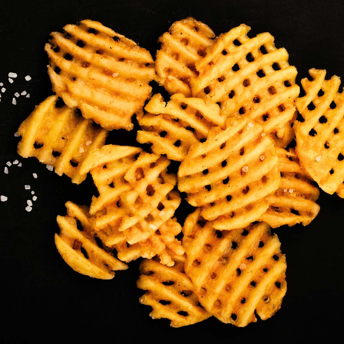 rondelles de pomme de terre gaufrées avec sel sur une planche de service noire