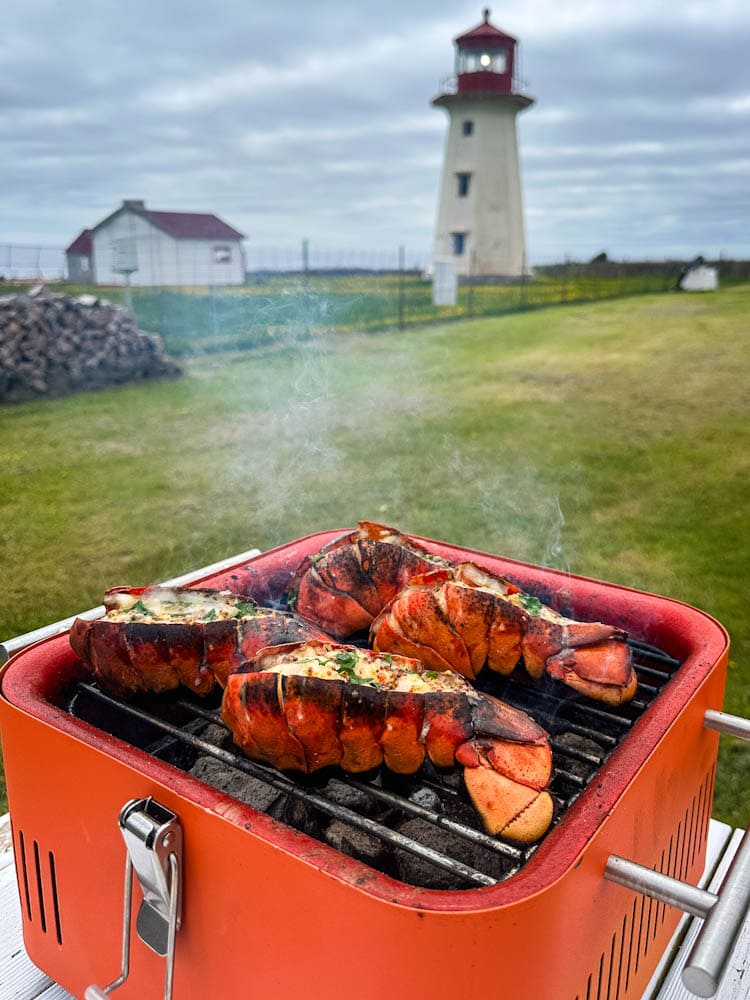 queues de homard grillé sur petit grill devant phare et la mer