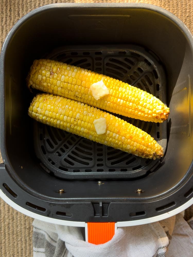 maïs entier (blé d'inde) grillé avec beurre sur le dessus dans le panier de friteuse à air chaud