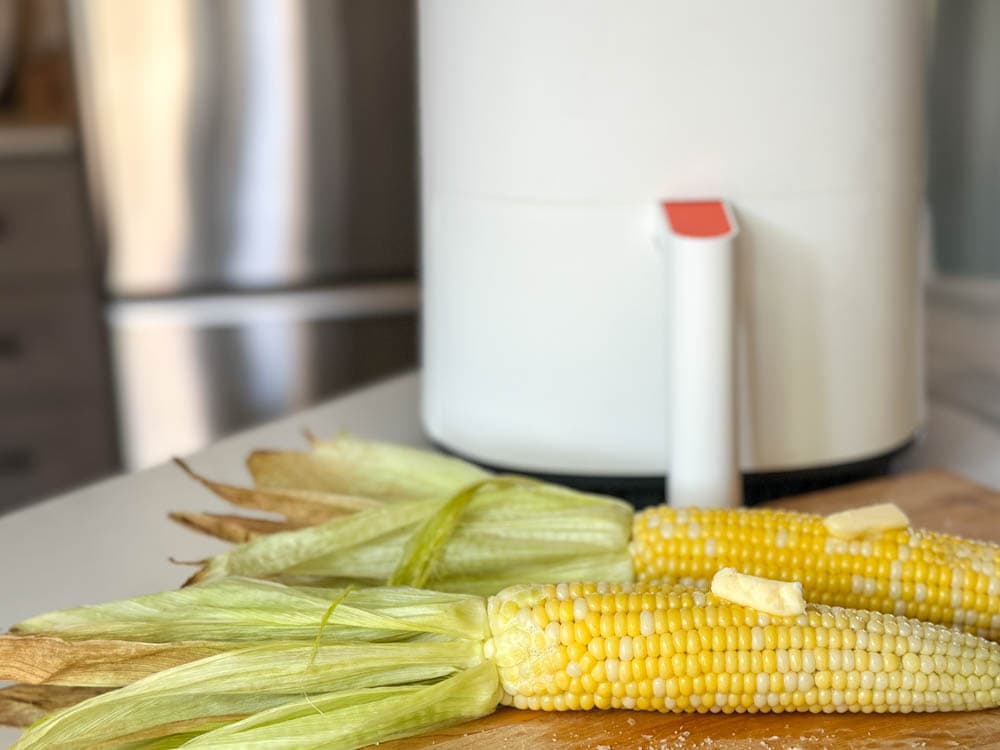 épis de maïs avec du beurre devant air fryer blanc