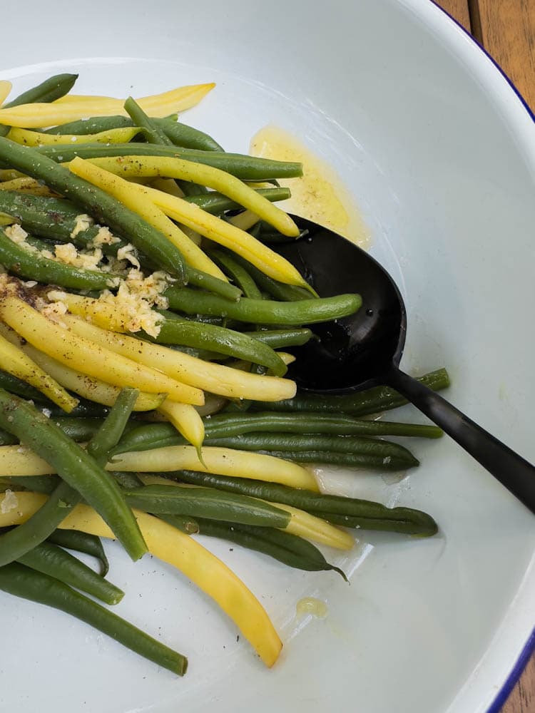 haricots jaunes et verts tièdes avec beurre et ail dans un bol de service avec cuillère