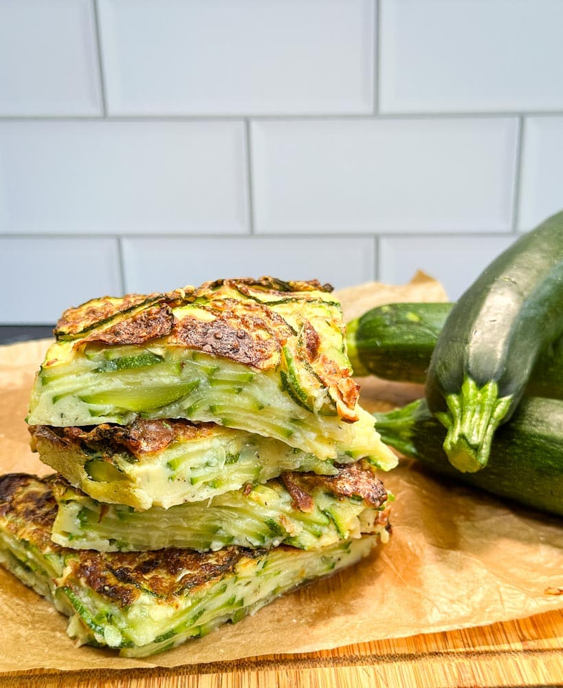 gratin de courgette en morceau sur une planche avec courgettes en arrière plan