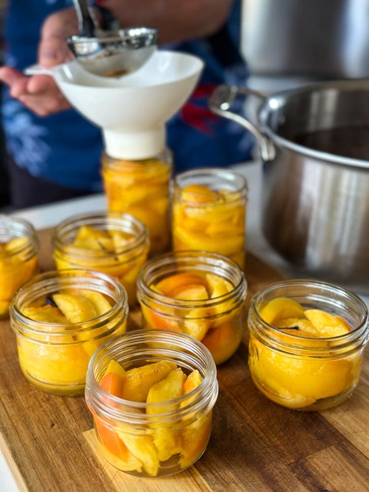 bocaux de conserve de pêches, verser sirop avec entonoir