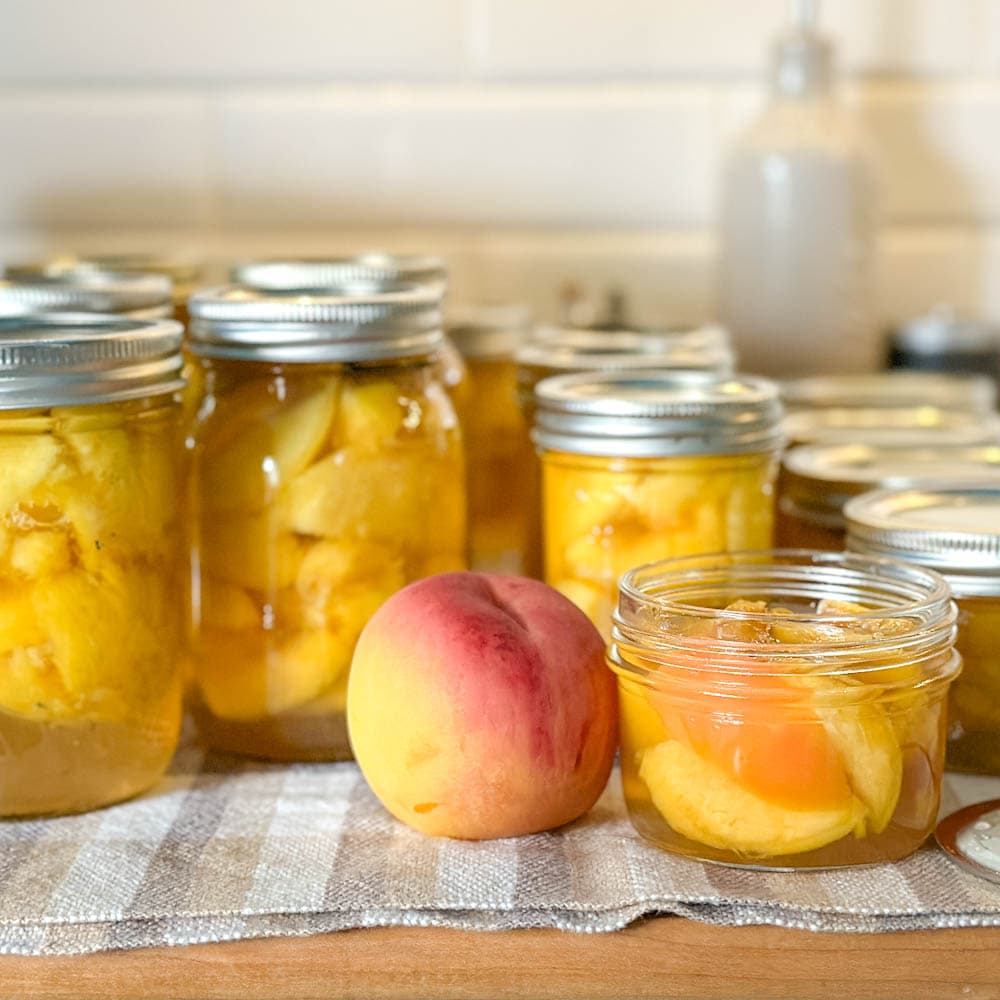 conserves de pêches dans le sirop à la vanille sur une planche avec une pêche en avant plan
