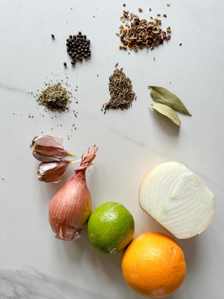 ingrédients carnitas: oignon, orange, lime, ail et épices sur un comptoir