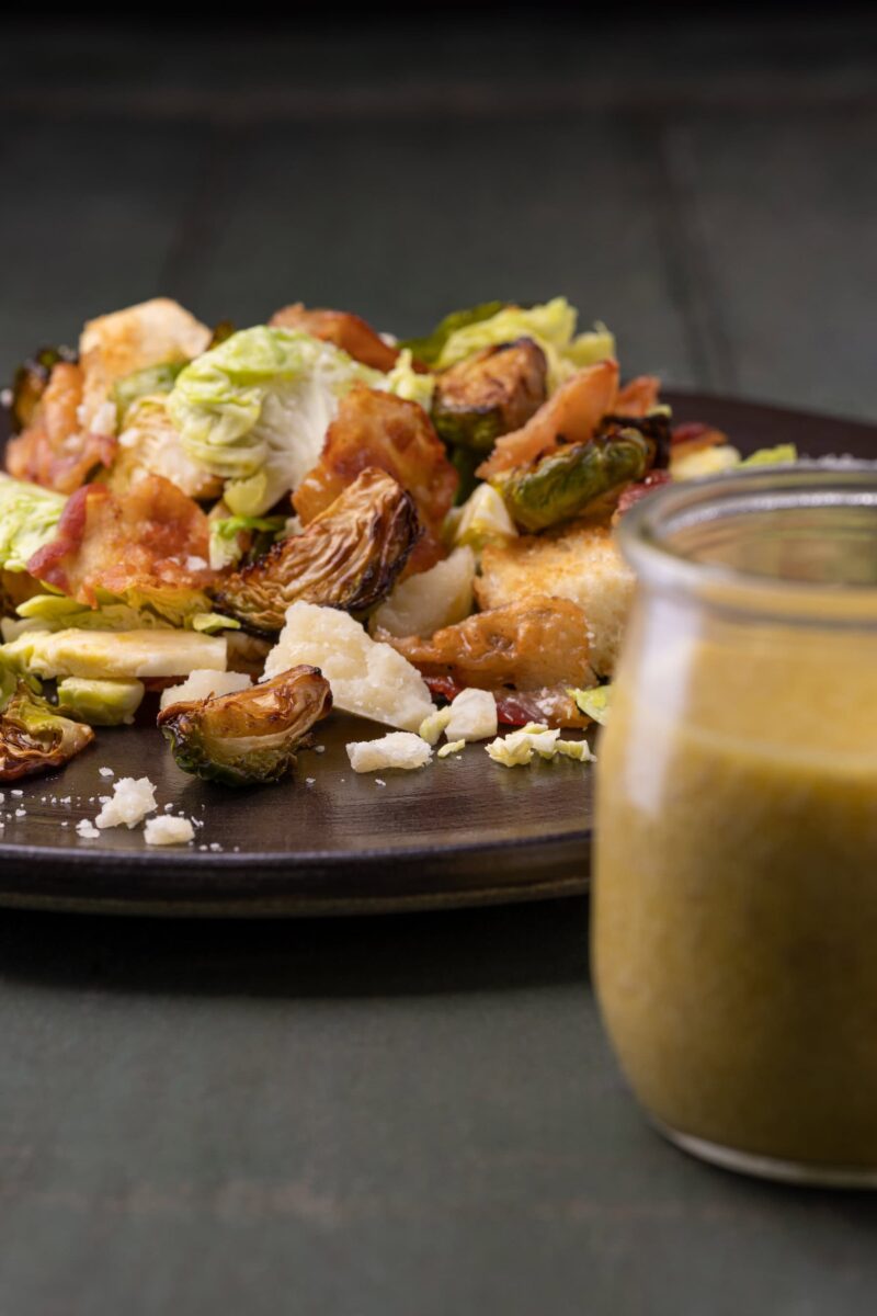 choux de bruxelles grillés au four en salade dans un bol, vinaigrette césar en premier plan