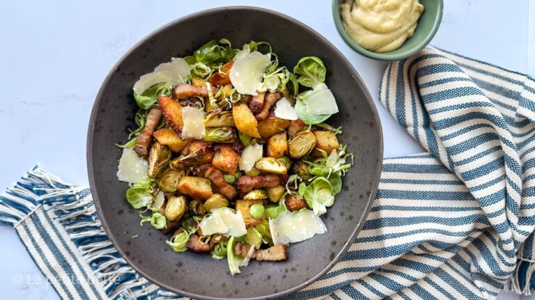 salade césar de choux de Bruxelles au air fryer, dans un bol noir avec croûtons, bacon, copeaux de parmesan et vinaigrette césar maison