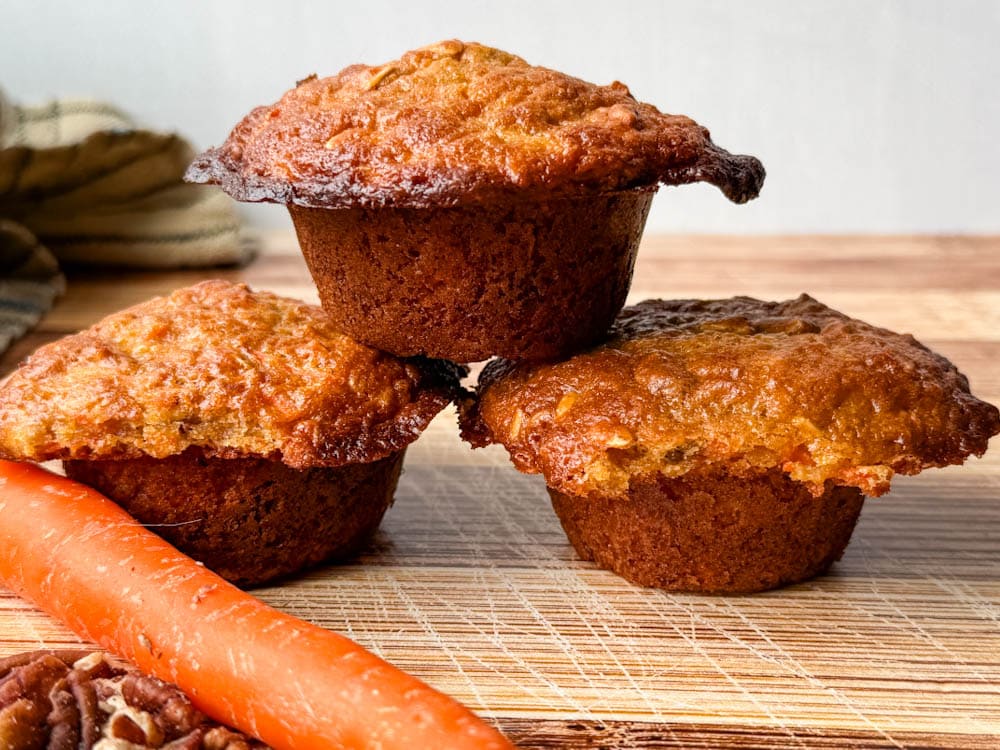 3 muffins aux carottes avec carotte sur une planche en bois