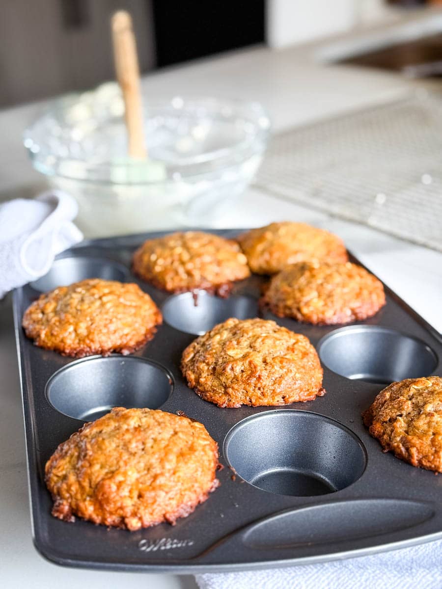 muffins aux carottes dans un moule à muffin en métal, bol de glaçage derrière
